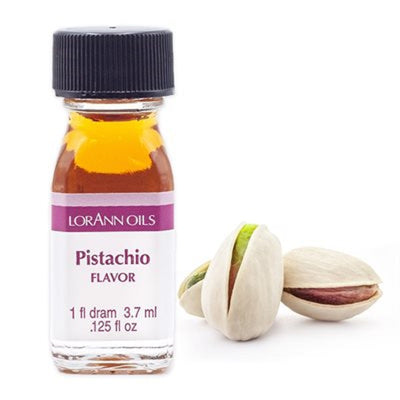 A bottle of Lorann Oils Pistachio flavoring next to some pistachio nuts.