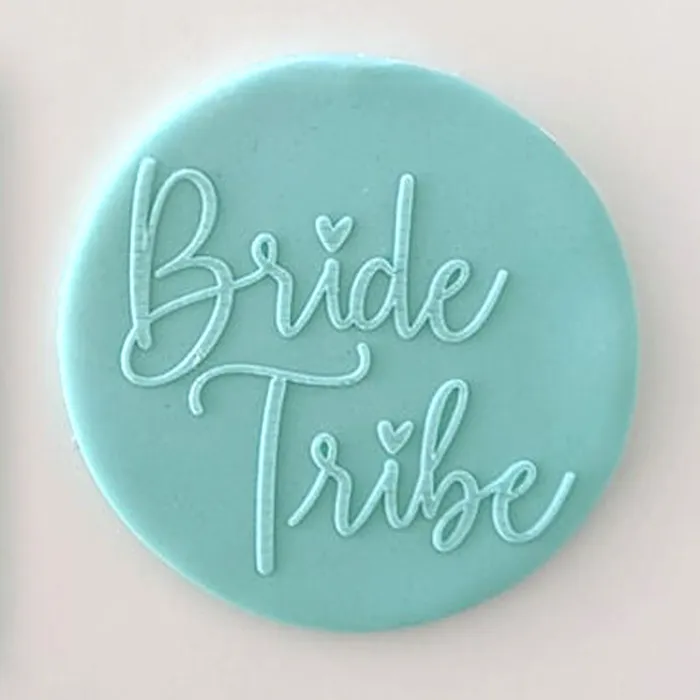 A round turquoise blue fondant plaque or sign with the words 'Bride Tribe' written in raised script, shown against a plain light background.