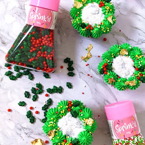 Cupcakes decorated with sprinkles for Christmas, alongside sprinkle jars