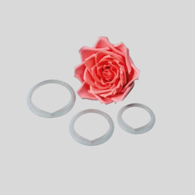 A pink gumpaste icingl rose flower displayed with three rose petal cutters on a light gray background.