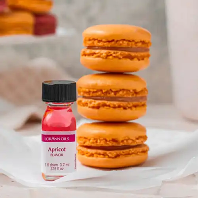 A bottle of LorAnn Oils apricot flavoring alongside 3 stacked apricot macarons.
