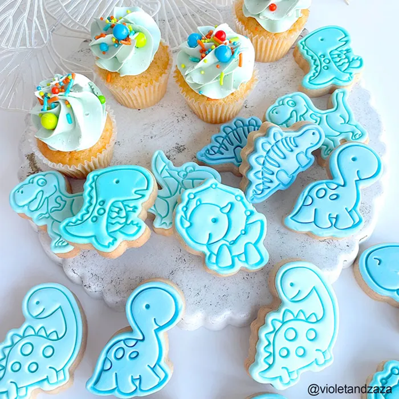 Blue fondant Dinosaur cookies paired with frosted cupcakes decorated with Dino Rawr Medley Sprinkles.