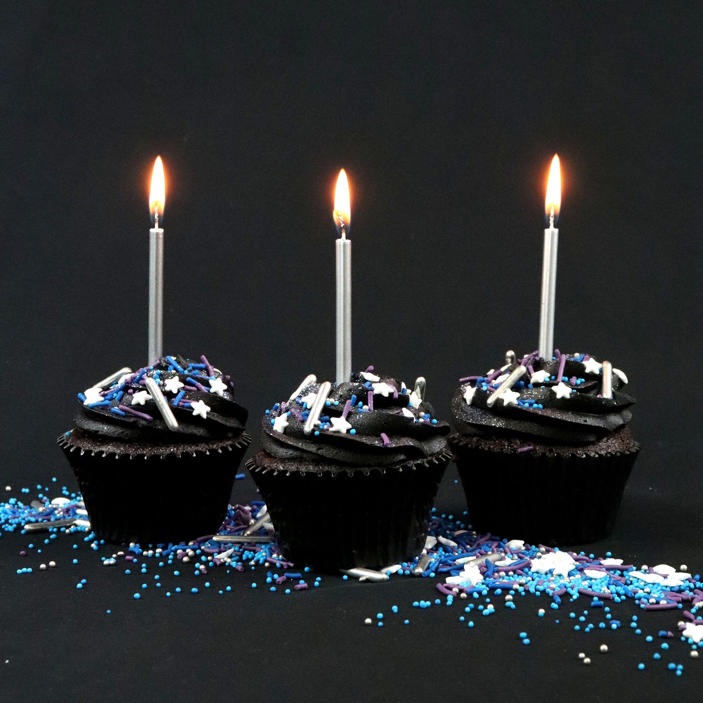 galaxy sprinkles on cupcakes with black icing and candles