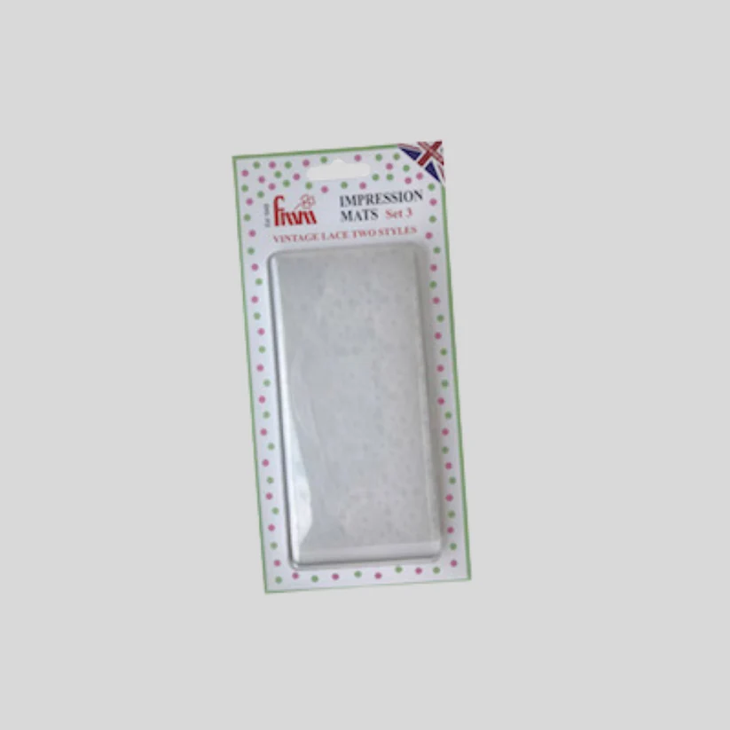 A packaged set of two vintage lace impression mats on a light gray background. The product is in its original retail packaging with a green and pink dotted border and a Union Jack flag in the top right corner.