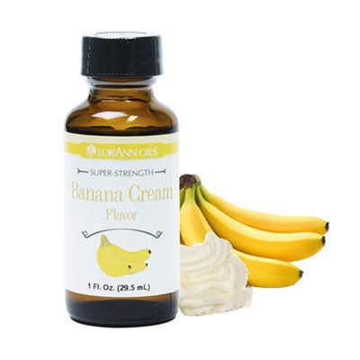 A bottle of Lorann Banana Cream Flavouring next to a banana and a dollop of whipped cream.