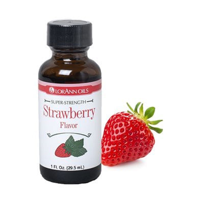 A bottle of Lorann Oils super strength strawberry flavoring, next to a fresh strawberry.