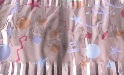 A close-up of a blush pink cake frill with printed musical notes and party balloons.
