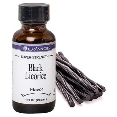 A bottle of Lorann Oils Black Licorice flavoring alongside several pieces of black licorice candy.