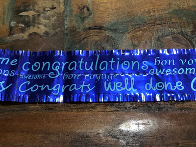 A royal blue cake frill with text that reads 'CONGRATULATIONS WELL DONE'.