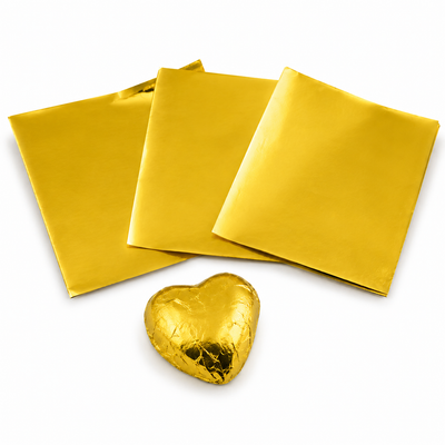 Three gold foil sheets and a heart-shaped chocolate bar wrapped in gold foil on a white background
