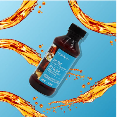 A bottle of Lorann Rum Emulsion flavouring against a blue background with stylized orange liquid swirls around it.