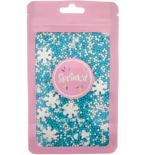 A pink resealable pouch filled with blue, white, and light blue sprinkles and white snowflake-shaped sprinkles, with a pink circular label reading 'Sprink'd' on the front.
