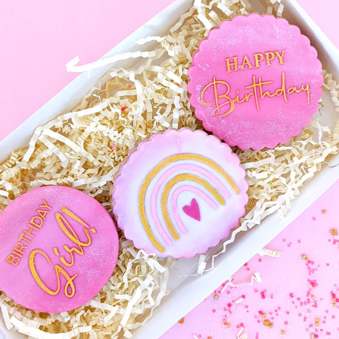 Pink cookies with 'Happy Birthday Girl' text in a decorative box on a pink background