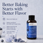 A bottle of Lorann Better Baking Starts with Better Flavor Blueberry flavoring extract is shown next to a glass of blue-colored batter and bowls of blueberries on a light gray background with promotional text.