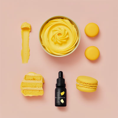 Yellow dessert items including a bowl, macarons, and a bottle on a pink background