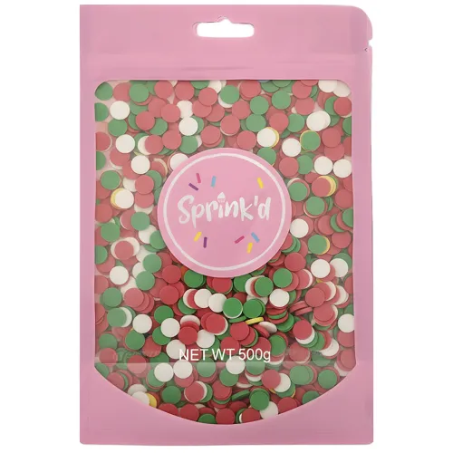 A 500g bag of Sprink'd holiday sprinkles, featuring a pink resealable stand-up pouch with a clear window showing the colorful round sprinkles inside. The sprinkles are primarily red, green, and white, with a pink circular label in the center featuring the 'Sprink'd' brand logo.