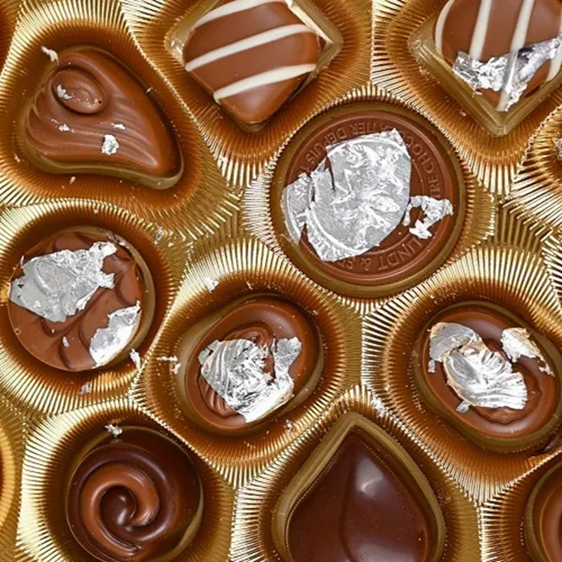 Assorted chocolates in a gold box decorated with Silver Leaf.