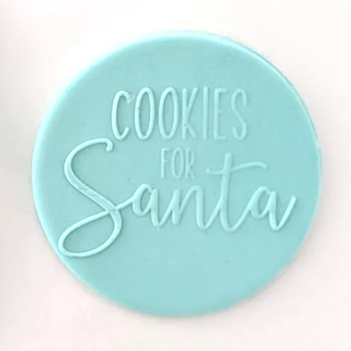A round light blue fondant plaque with the words 'COOKIES FOR Santa' embossed in the center, shown on a plain light background.