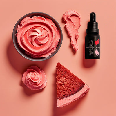 Red velvet cake with pink frosting, a bottle of Sprinksgel color, and a swatch of pink frosting on a peach background.