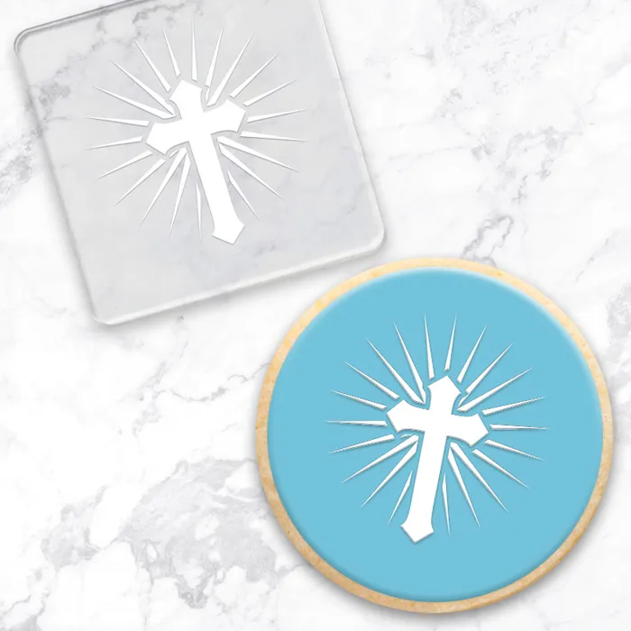 Clear acrylic debosser with cross design on a marble surface. Alongside a finished cookie made using the tool