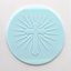 A circular light blue fondant disc featuring an embossed cross with radiating lines, shown on a plain off-white background.