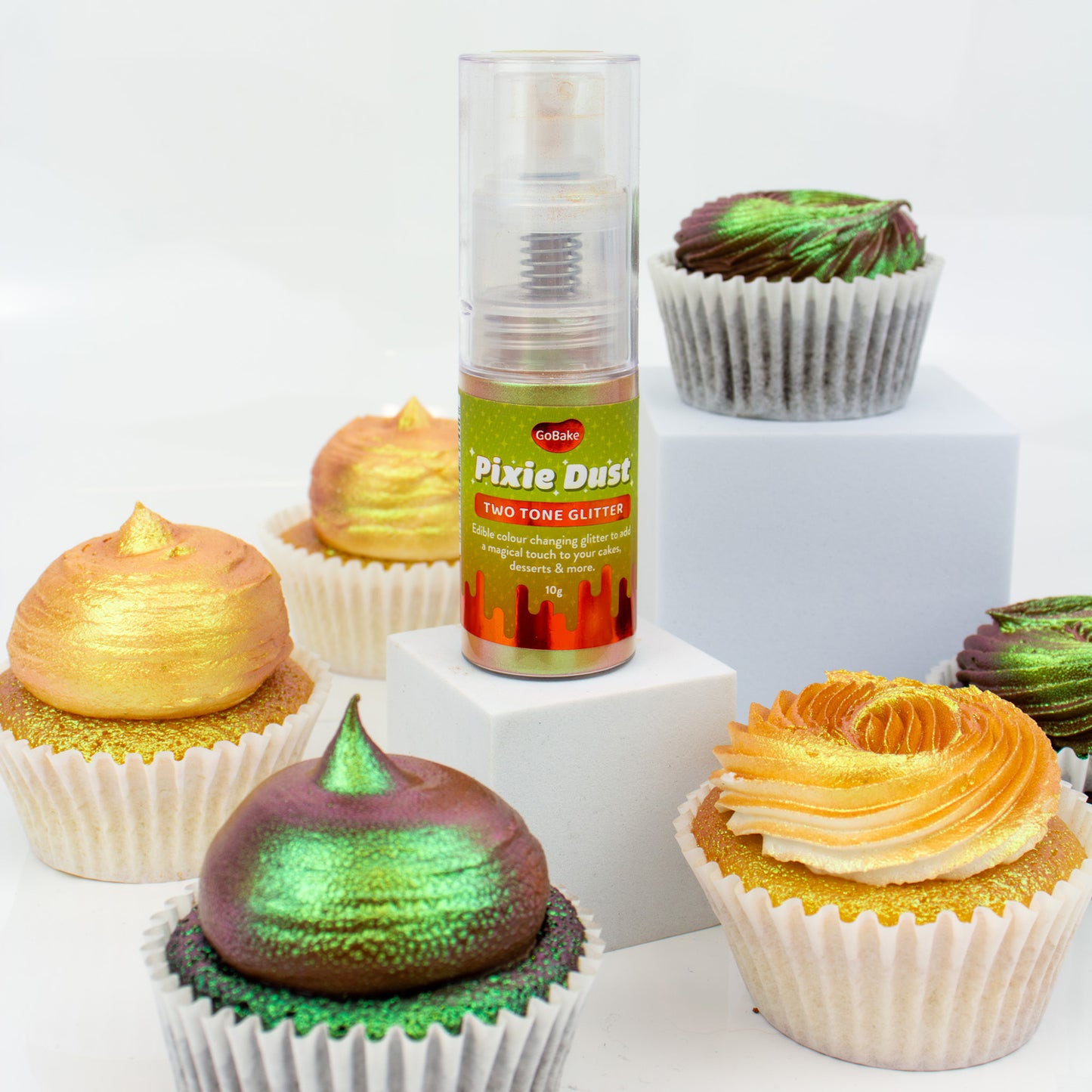 Cupcakes with colorful frosting and a bottle of Pixie Dust glitter on a white background
