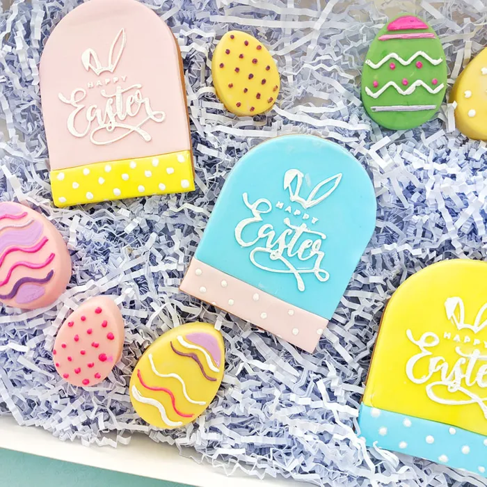 Easter themed cookie set in bright colours. Some read Happy EAster. Others are shaped like eggs.