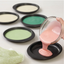 Pink cake batter being poured into a cake pan with other coloured batters in molds on a white background.