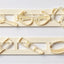 A set of cream-colored gumpaste icing cutters arranged in two rows on a light gray background. Including a ring, hair brush, lip stick, hair dryer, scissors, shoes, hand mirror, sunglasses, hand bag, and summer hat.