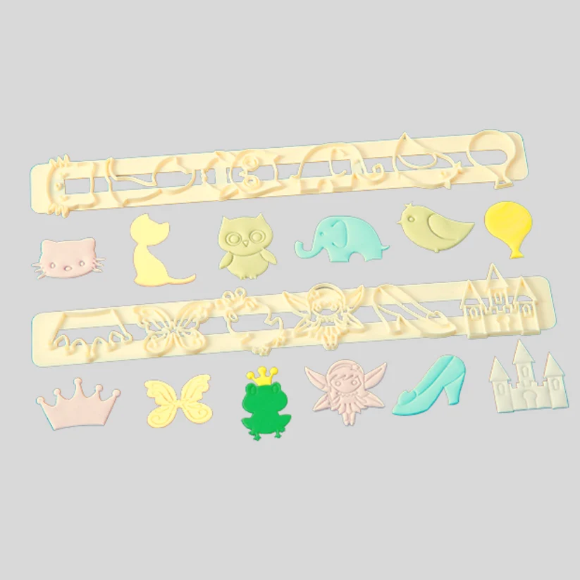 A set of pale yellow plastic gumpaste cutters and molds arranged on a light gray background, with matching small cutout shapes below including a cat, cat silhouette, owl, elephant, bird, balloon, crown, butterfly, frog, fairy, high heel, and castle.