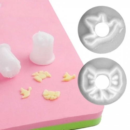 A pink and green sugarcraft mat with small pale yellow gumpaste icing pieces, alongside two circular cutters showing the corresponding shapes. 