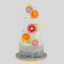 A three-tier white cake decorated with large pink, orange, and yellow sugar flowers, featuring a gray ruffled bottom border and a gray cake board, set against a solid gray background.