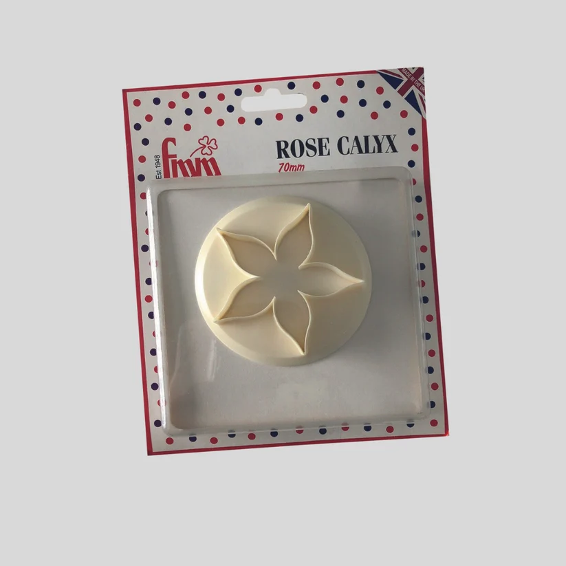 An off-white plastic rose calyx baking tool, still in its original retail blister packaging with a red, white, and blue polka dot border, shown against a solid gray background.