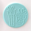 A round light blue fondant circle featuring embossed gift box designs with bows and hearts, shown on a plain light pink background.