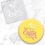 A clear acrylic debosser that reads Happy Easter, with a set of Bunny ears. Alongside a yellow finished cookie, made with the tool
