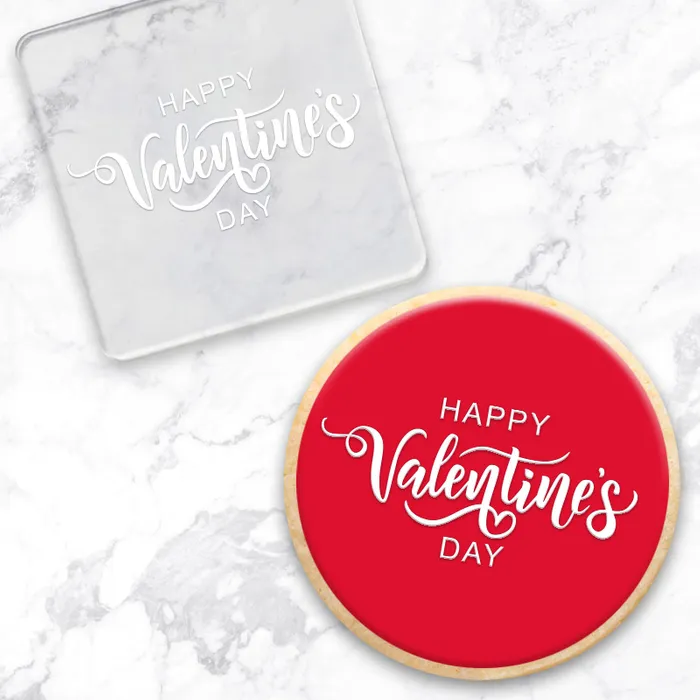 Clear acrylic debosser. That reads Happy Valentine's day. Alongside a red cookie showcasing its use.