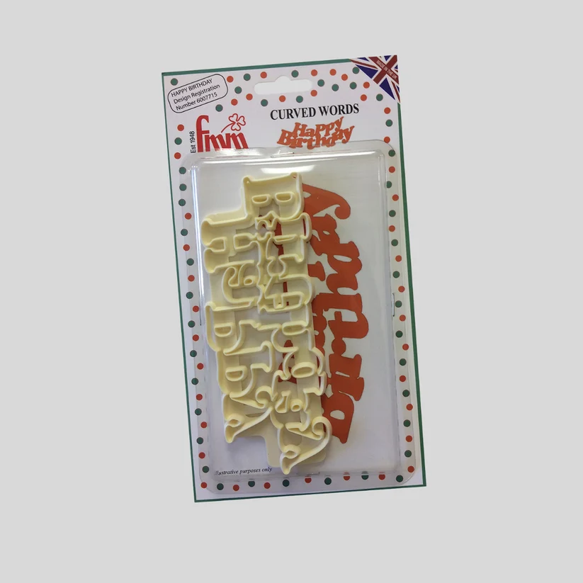 A packaged set of two 'Curved Words' plastic letter cutters spelling 'Happy Birthday' in pale yellow and dark red, mounted on a white backing card with a green border and red dots.