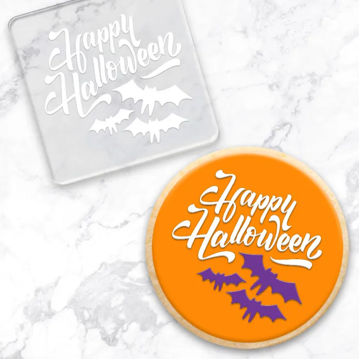 Happy Halloween clear acrylic debosser tool. Alongside an orange cookie showcasing the design with bats