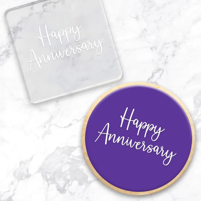 clear acrylic debosser with Happy Anniversary written on it. Alon with a finished purple cookie showcasing the design