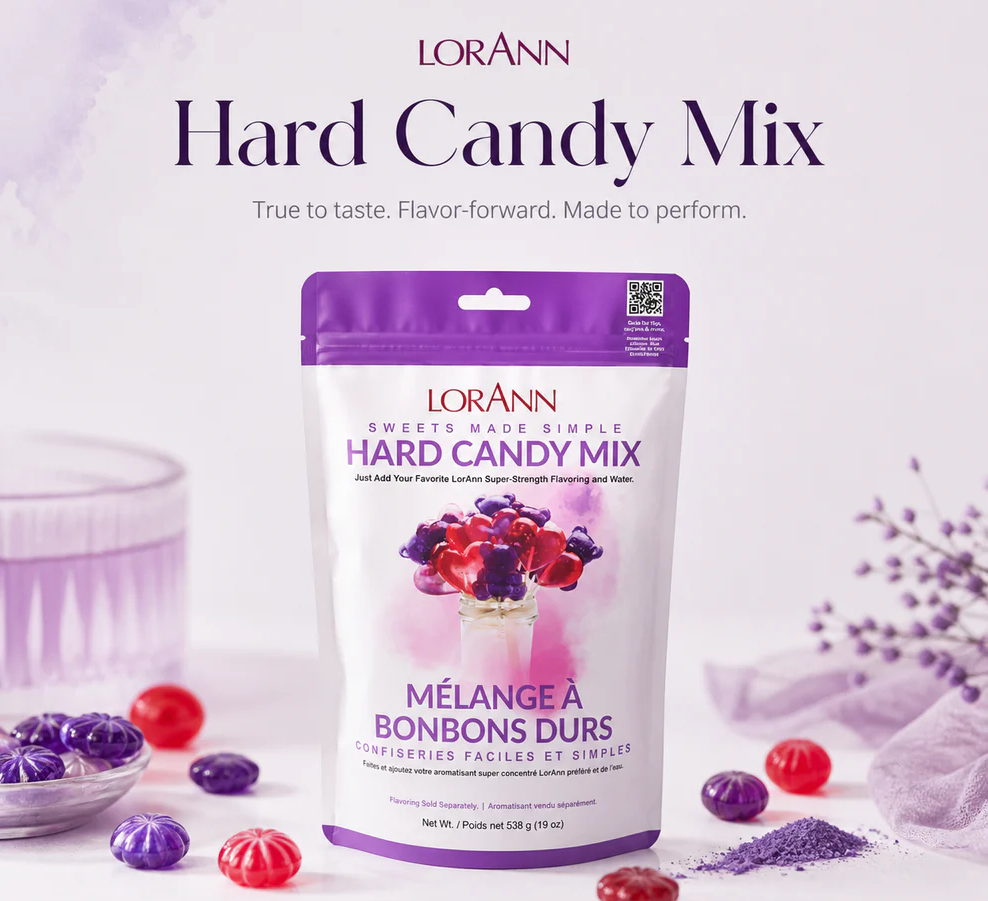 A stand-up pouch of LorAnn Hard Candy Mix centered on a soft lavender background with decorative candy pieces and lavender sprigs around it. Large text at the top reads 'LorAnn Hard Candy Mix' with a tagline below.
