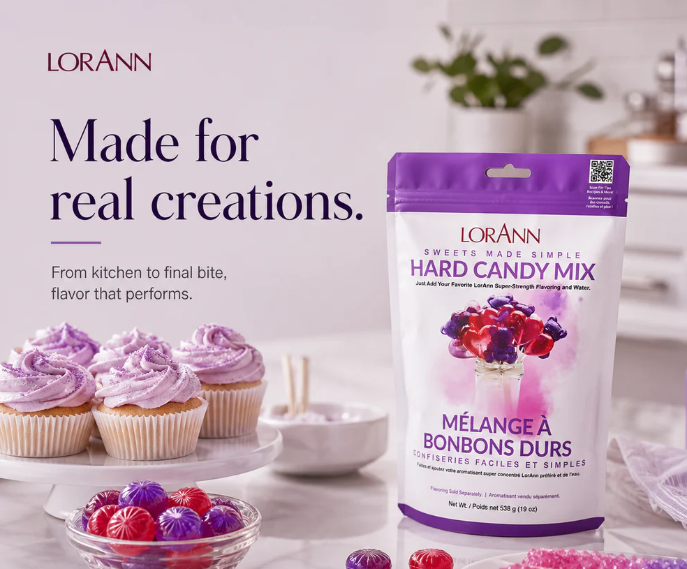 LORANN Hard Candy Mix in a purple and white resealable bag, displayed next to decorated cupcakes, a bowl of colorful hard candies, and loose candy pieces on a light studio background with blurred decorative elements.