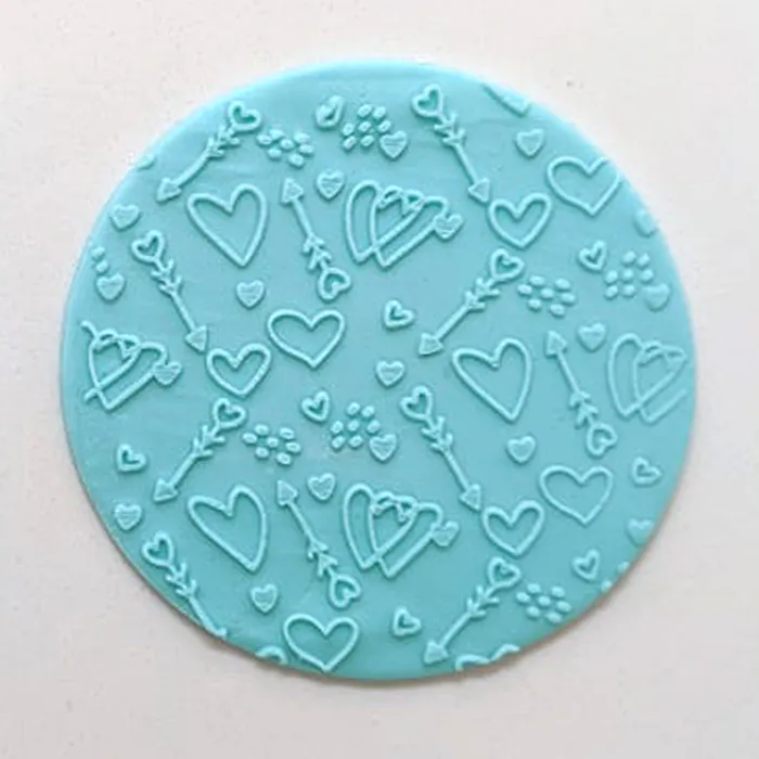 a blue fondant plaque with an embossed pattern of hearts