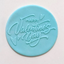 A round light blue fondant plaque with embossed cursive text reading 'HAPPY Valentine's Day' and small heart details, shown on a plain light background.