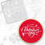 A clear acrylic debosser tool that reads, Happy Valentine's day. Alongside a red cookie showcasing the design