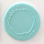 A geometric wreath with leafy branches design shown on a teal fondant icing plaque