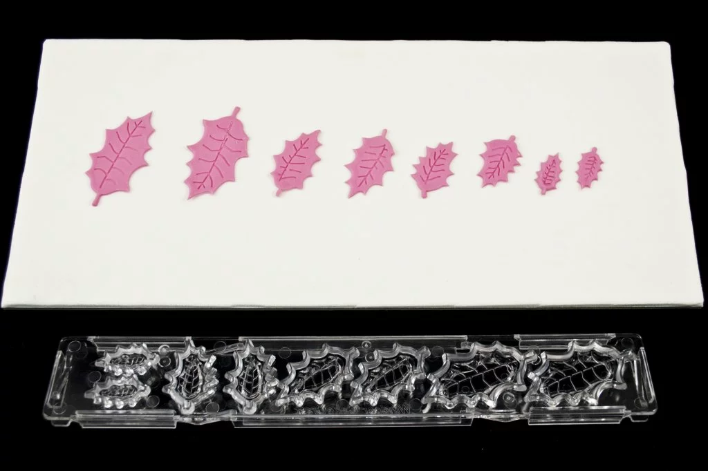 Holly leaf plastic clikstix cutter. Alongside pink fondant icing examples of each leaf size