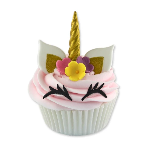 A unicorn-themed cupcake decoration or cupcake topper featuring pink frosting swirls, a gold horn, white ears with gold glitter accents, small pink and purple flowers, and black eyelashes on a white cupcake liner, isolated on a white background.