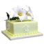 A square pale yellow-green cake decorated with white lily flowers and green leaves on top, set against a plain white background.
