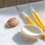 A football-themed pop it mould cutter by Jem alongside a fondant example of a small brown rugby football with 'PARTY GO!' written on it, and two yellow-handled metal tools, all arranged on a white textured mat.