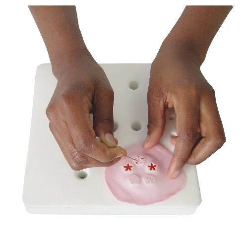 Jem roller pad with a cutter and icing in place, with someone making small blossom icing flowers